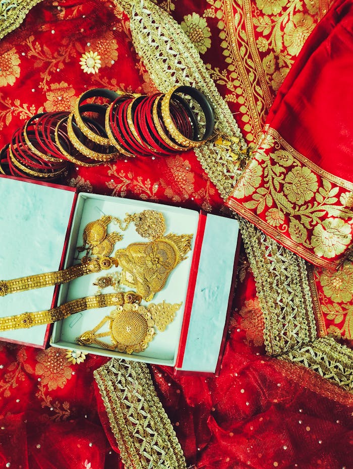 Luxurious Indian bridal jewelry with gold necklaces and bangles elegantly laid out on a rich red saree.