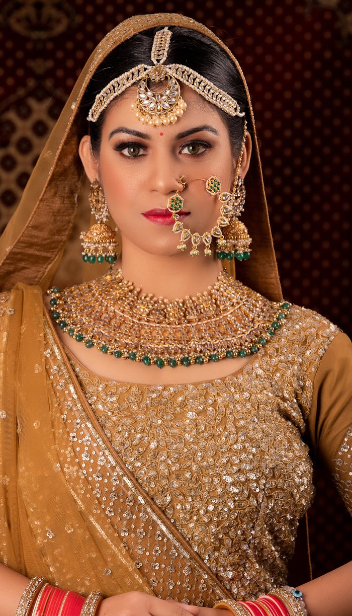 Portrait of a South Asian woman wearing traditional Indian saree and jewelry in a studio setting.